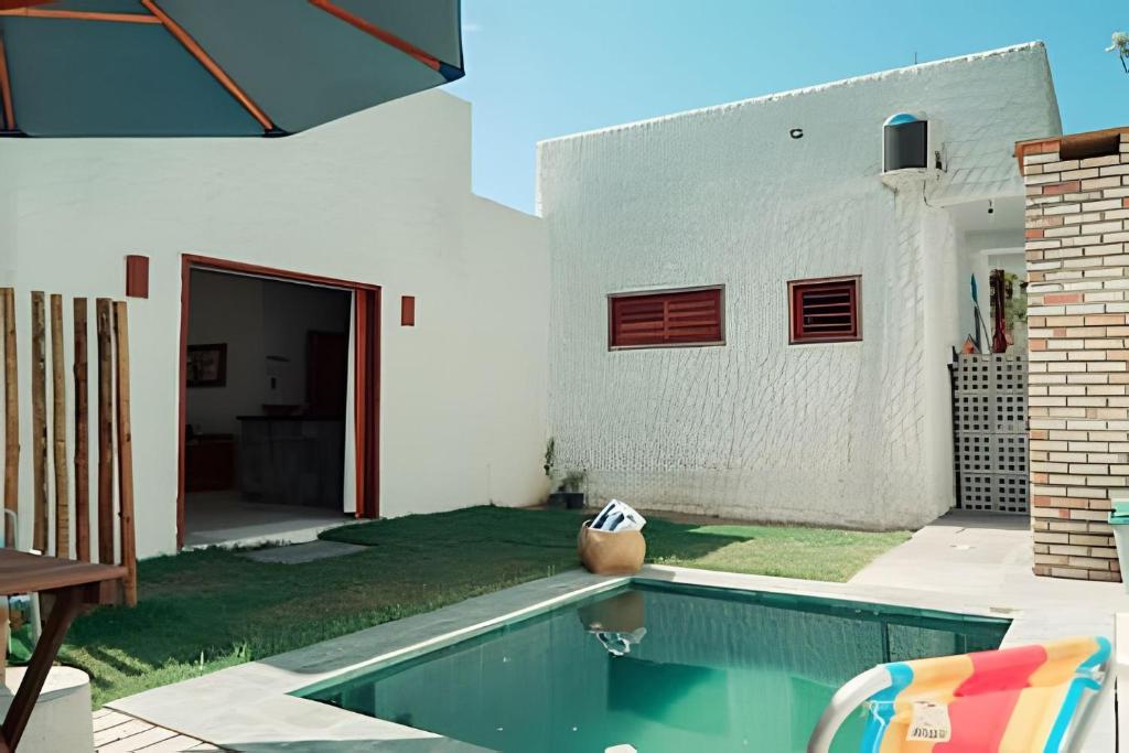 a backyard with a swimming pool and a white house at Casa agradável, no centrinho de Barra Grande in Barra Grande