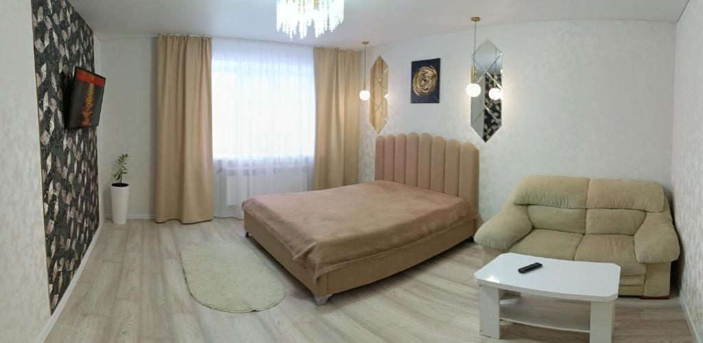 ein Schlafzimmer mit einem Bett, einem Sofa und einem Stuhl in der Unterkunft 1-комнатная квартира мкр. Аэропорт in Qostanai