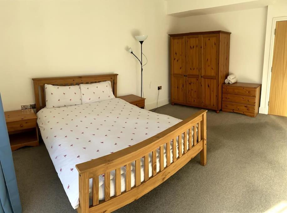 a bedroom with a wooden bed and a dresser at Huge Flat Sleeps 6+ free parking in Nottingham