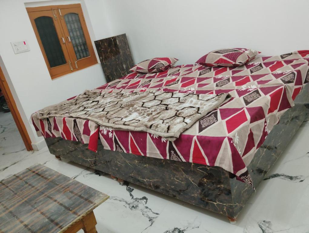 Ram Tilak homestay في Faizābād: سرير في غرفة ولحاف احمر وابيض