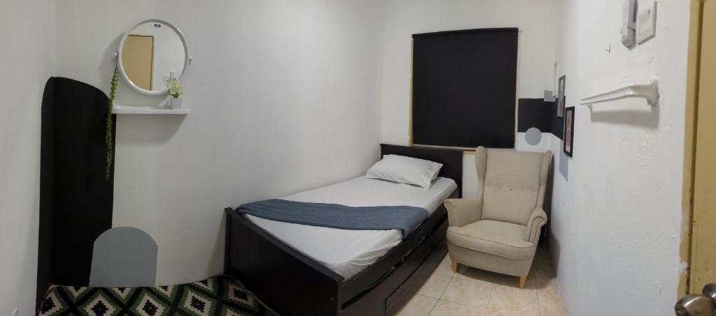 ein kleines Schlafzimmer mit einem Bett und einem Stuhl in der Unterkunft Rest D'Nufa in Semenyih
