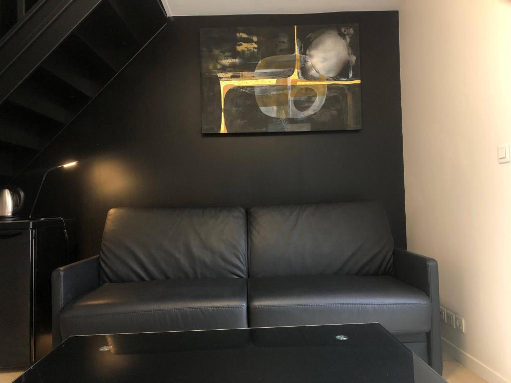 uma sala de estar com um sofá e uma fotografia na parede em Une chambre à Neuilly Guest house em Neuilly-Plaisance