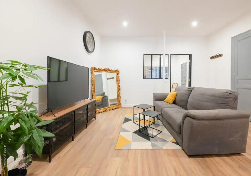 a living room with a couch and a flat screen tv at SYDNEY in Montargis