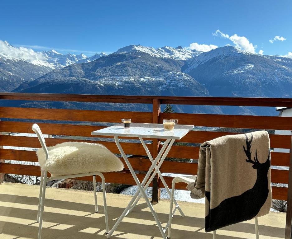 a table and chairs on a balcony with mountains at The Fit’ house in Crans-Montana