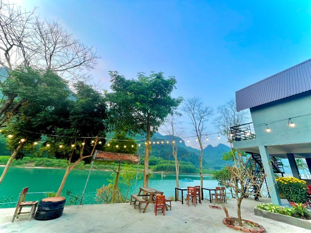 a patio with tables and chairs next to a lake at Little Rock Homestay in Phong Nha