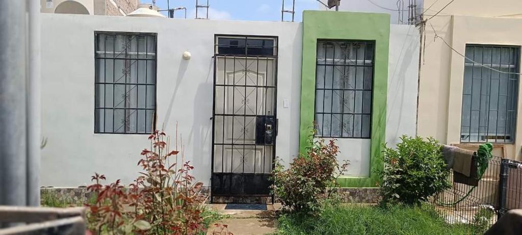 a white house with green and black doors at Villa del Sol de Ica in Ica