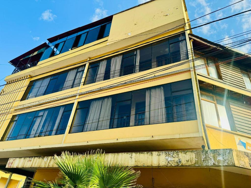 阿魯沙的住宿－Arusha Backpackers Hotel，一座黄色的建筑,有很多窗户