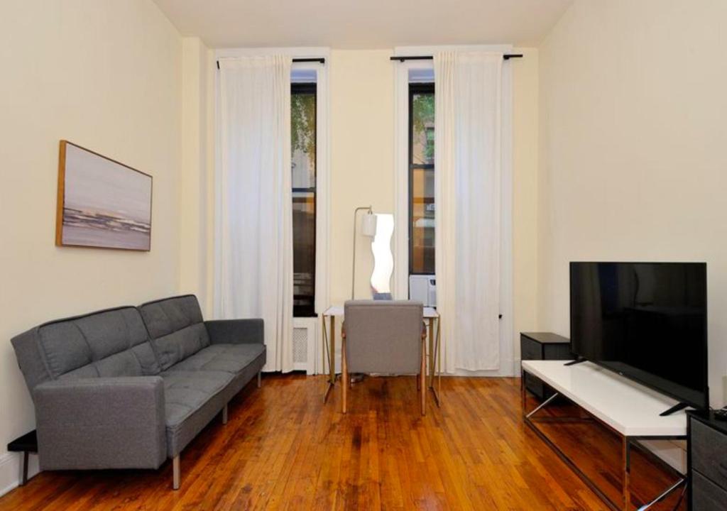 a living room with a couch and a flat screen tv at Modern 2 Bedroom Apartment in Midtown West in New York