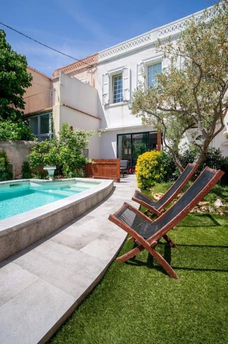une paire de chaises assises dans l'herbe à côté d'une piscine dans l'établissement Maison air conditionné, piscine, quartier calme proche des plages, à Marseille