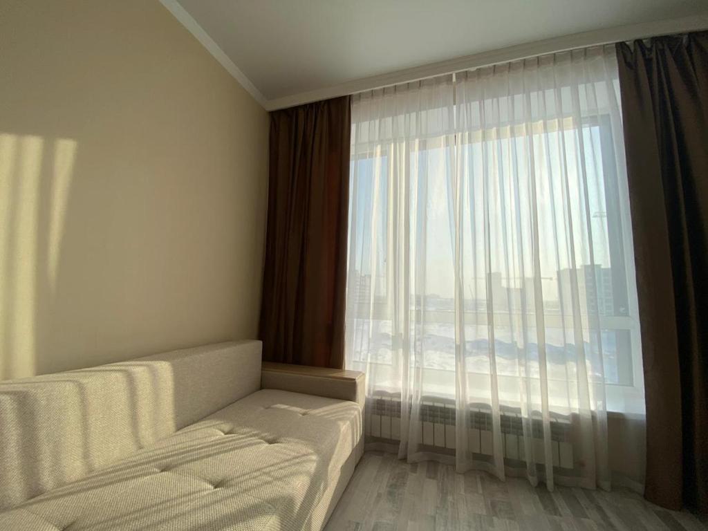 PrigorodnyyにあるЖК Sati Club Houseの大きな窓、ソファ、ベッドが備わる客室です。