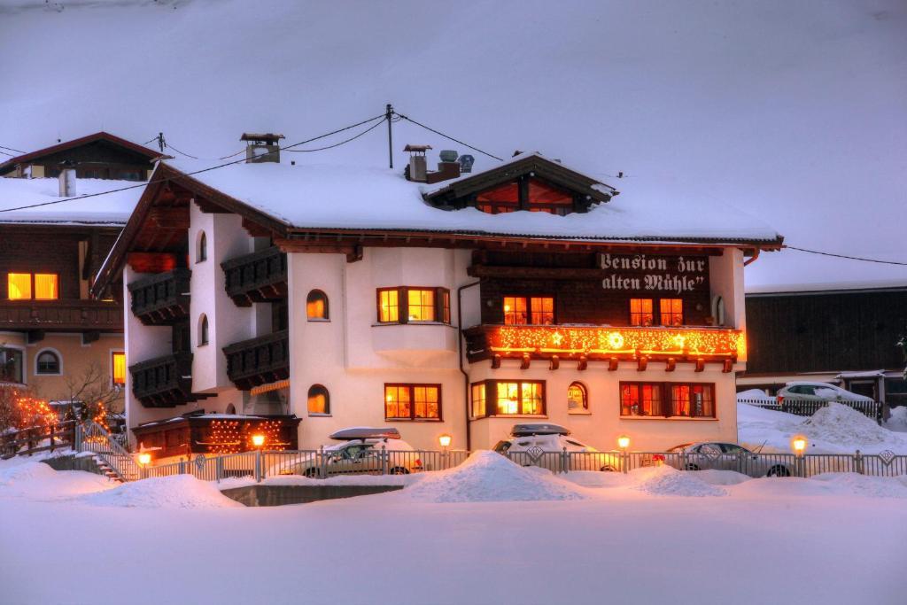 un gran edificio con nieve delante en Pension Zur alten Mühle, en Sölden