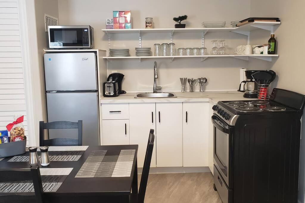 a kitchen with a refrigerator and a table and a sink at Cozy home on a quiet street minutes to DT Kingston in Kingston