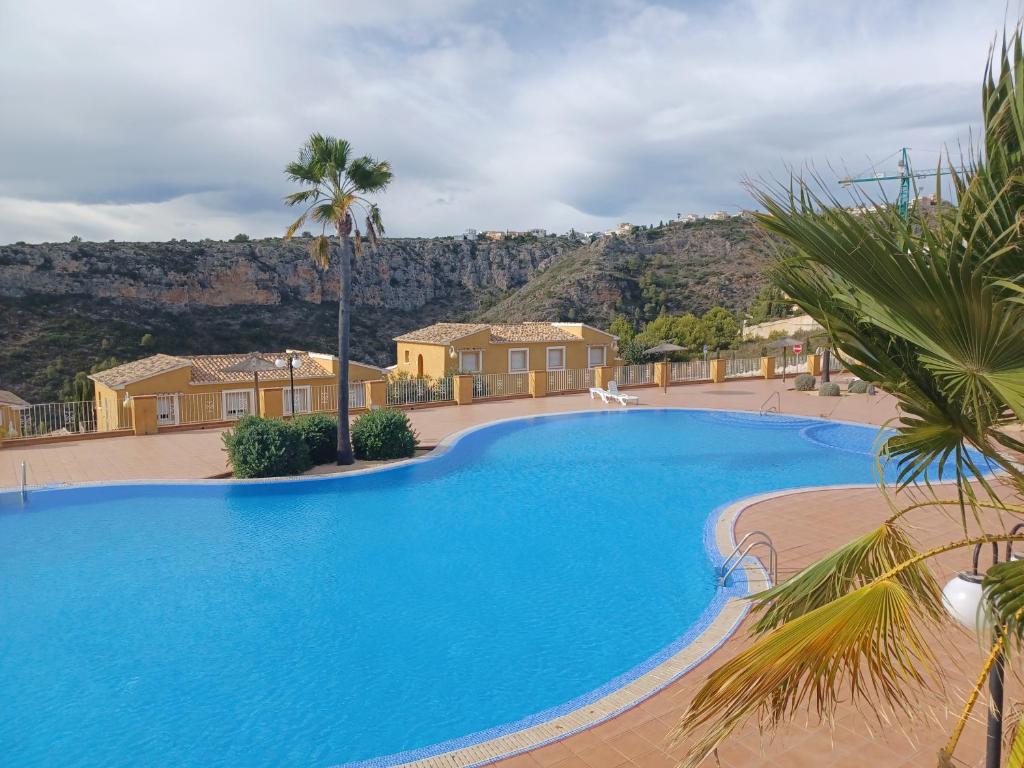 une grande piscine bleue avec une montagne en arrière-plan dans l'établissement Apartment Casa Lieja - Cumbre del Sol, à Cumbre del Sol