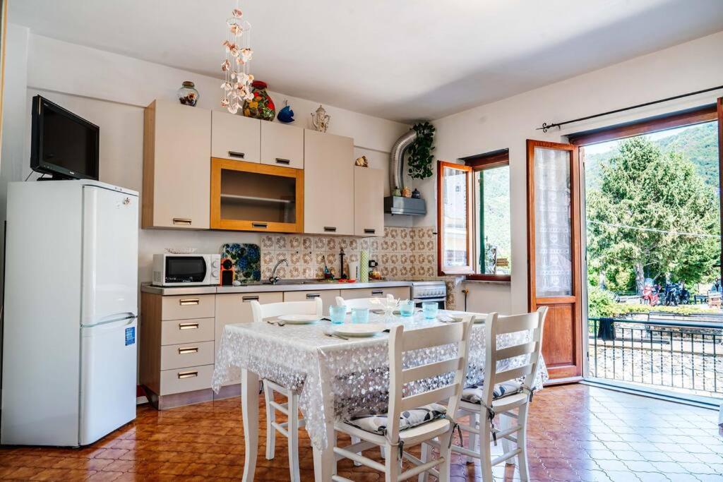 eine Küche mit einem Tisch und Stühlen sowie einem weißen Kühlschrank in der Unterkunft [Turri House]-wifi-garden-barbecue-parking in Vescina