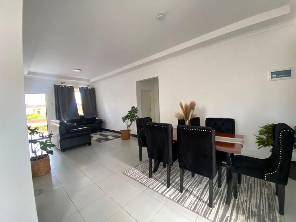 a living room with a dining room table and chairs at Queen City Homes in Lilongwe
