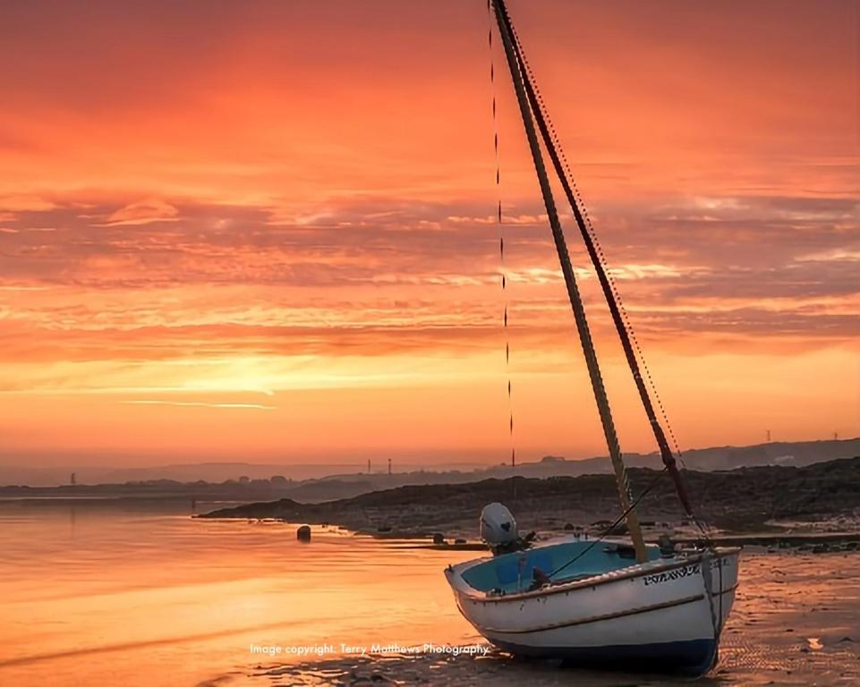 ein Boot am Strand bei Sonnenuntergang in der Unterkunft Catboat Cottage in Appledore