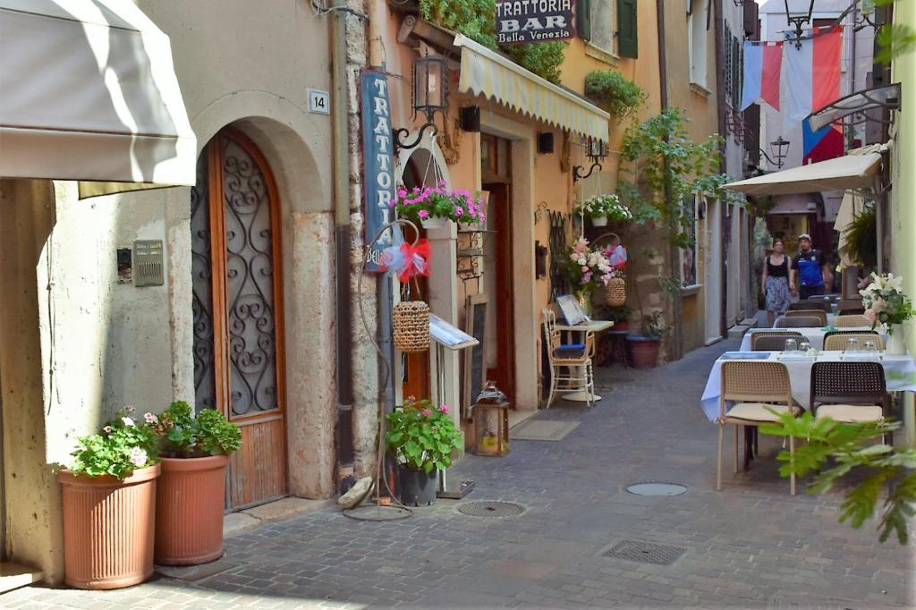 een steegje met tafels en stoelen in een straat bij Casa Marina - Holiday Rental in Garda