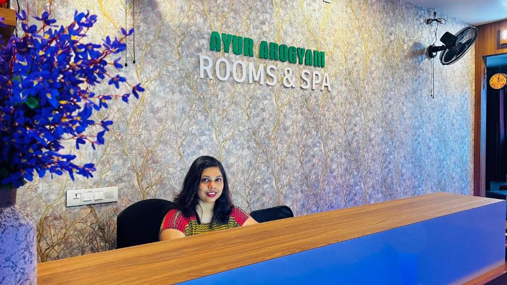 una mujer sentada en un escritorio en una habitación en Ayur Arogyam Rooms and Spa, en Kondotti