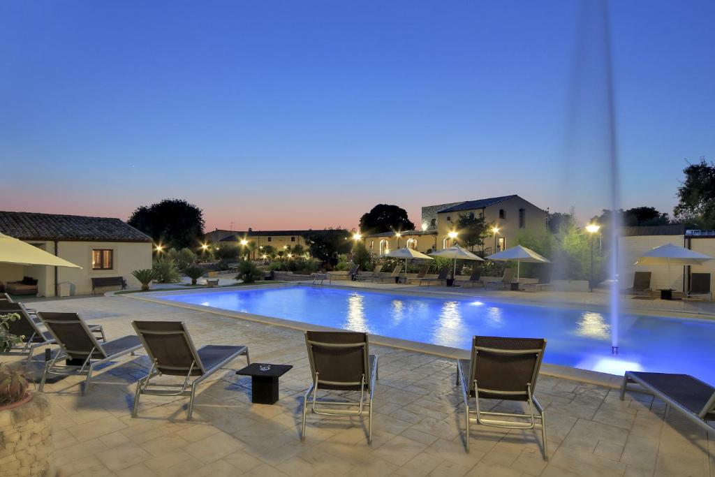 a pool at night with chairs and umbrellas at Artemisia Resort in Puntarazzi