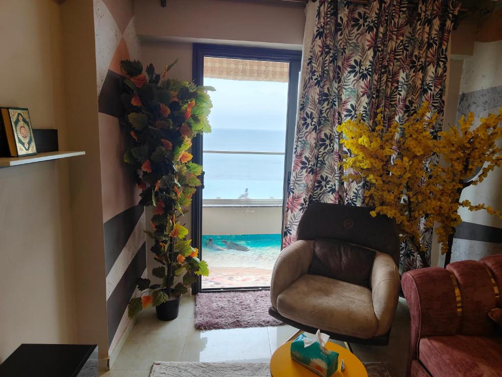 een woonkamer met een stoel en een raam bij شقة فندقية بحر مباشر in Alexandrië