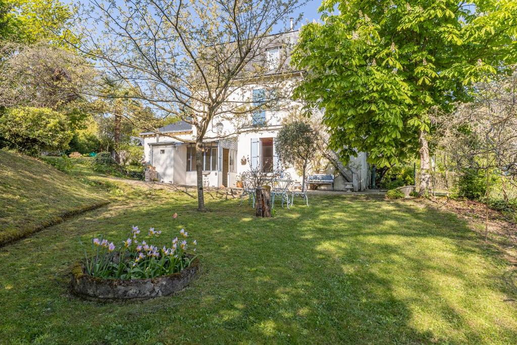 een huis met een tuin met bloemen in het gras bij Ker Mimi - Maison familiale atypique in Mûrs-Érigné