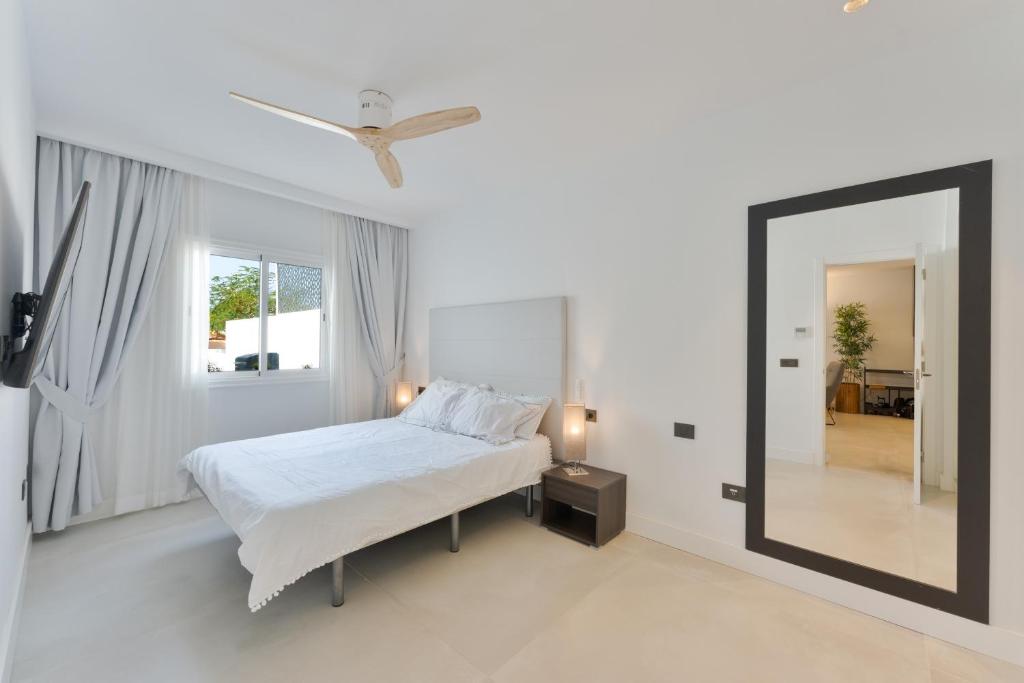 a white bedroom with a bed and a mirror at Designer loft with pool, with gigantic terrace and private parking & in the city centre in Adeje