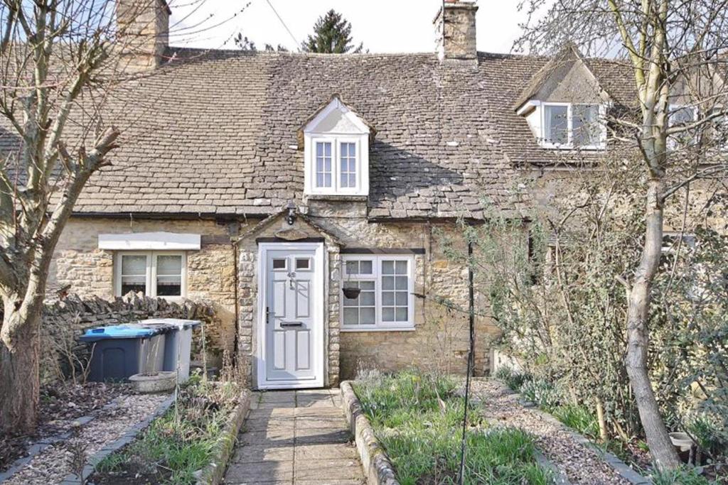 an old brick house with a white door at Remarkable 1-Bed Cotswolds Cottage in Finstock in Chipping Norton