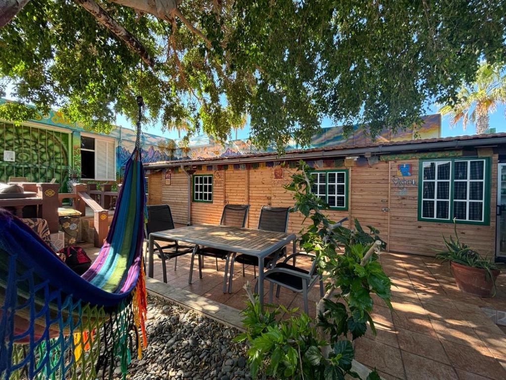 un patio con una mesa y una hamaca en Hostel Los Duendes del Sur, en Costa del Silencio