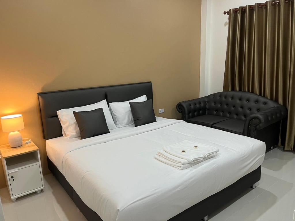 a bedroom with a large bed and a chair at The P2 Hotel in Mae Sot