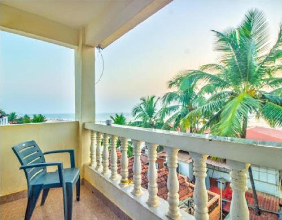 a balcony with a chair and a palm tree at Hotel Adam's Baga Beach Resort Goa - 2 minutes walk from Baga Beach in Baga