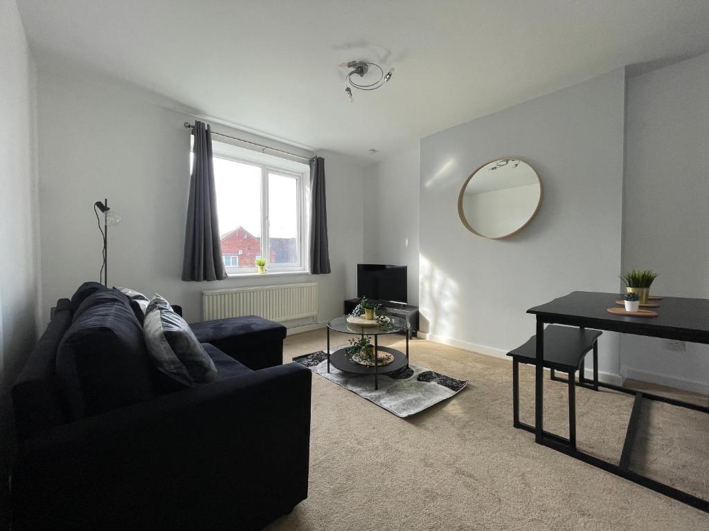un soggiorno con divano nero e specchio di Spacious 2BR Apartment w/Parking Near City Centre a Sheffield