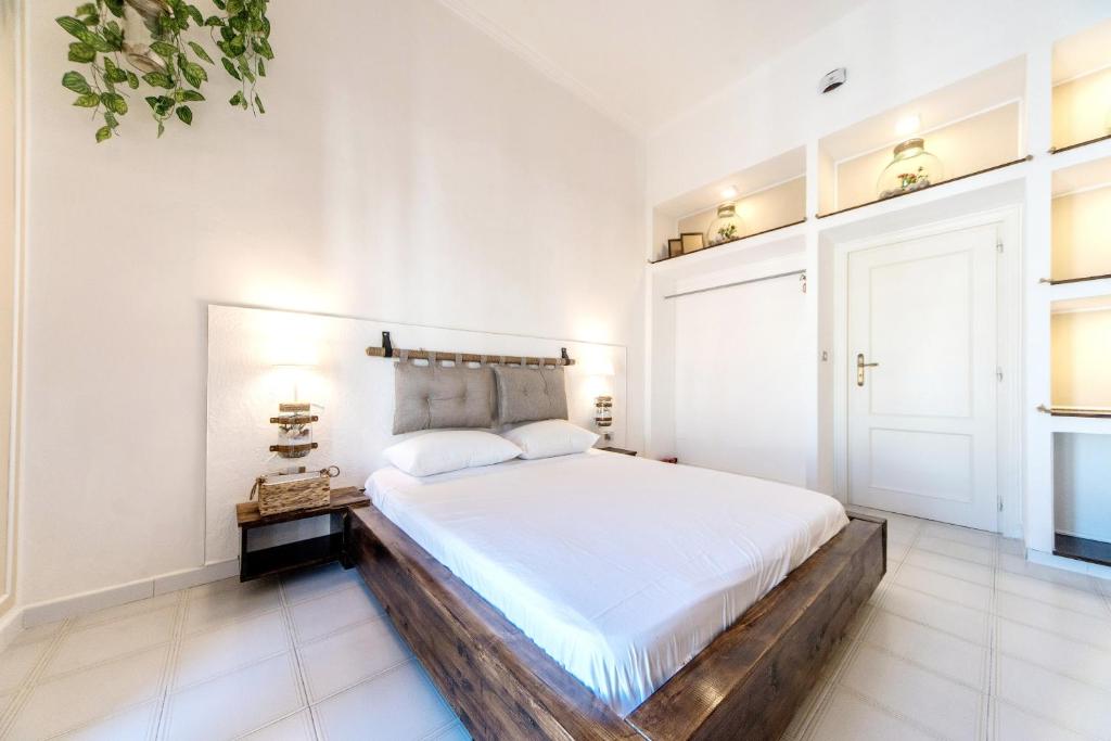 a white bedroom with a large bed with a wooden headboard at B&B Camera a Sud Iris in Trani