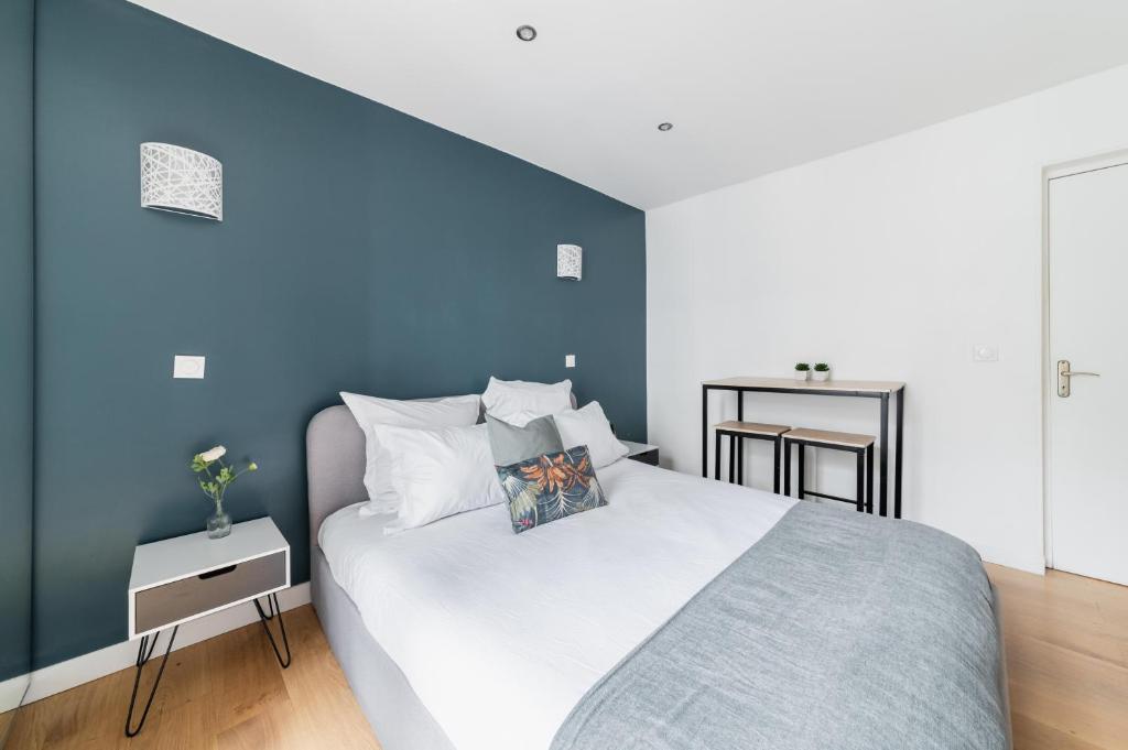 une chambre avec un grand lit avec un mur bleu dans l'établissement Imhost 6 - Charming Appartement Batignolles, à Paris
