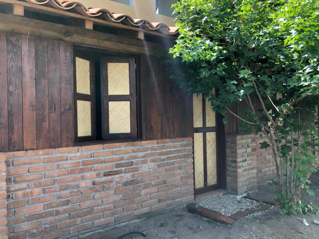 una pared de ladrillo con dos ventanas y un árbol en Hab #9 La Casa Del Profe Salo en Santa María Tonameca