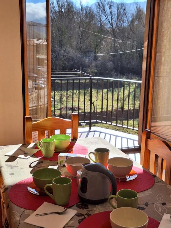 a table with bowls and cups on a table with a window at apartament Eliette 3 in Bagá