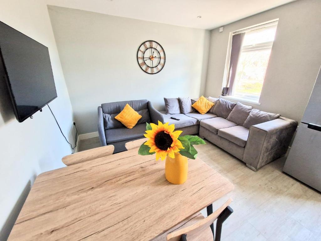 a living room with a couch and a table with a sunflower at Central Reading Modern flat - Walk to station and high street in Reading