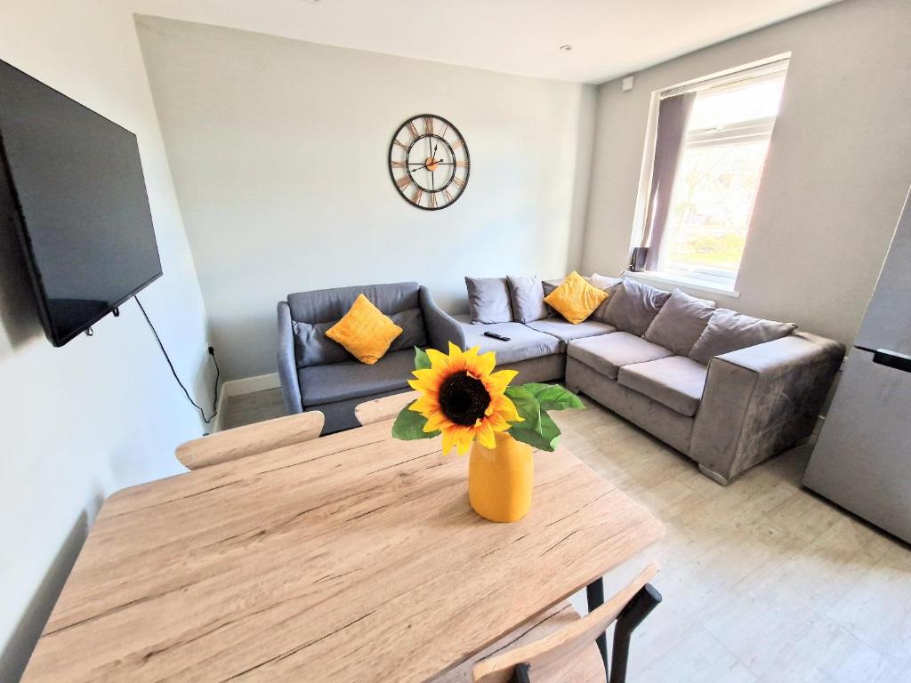 a living room with a couch and a table with a sunflower at Central Reading Modern 3BR flat - Walk to station and high street in Reading