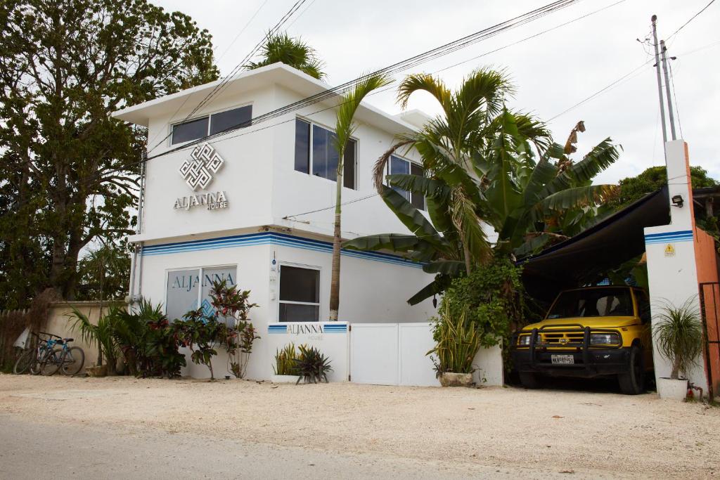 a white house with a yellow car parked in front of it at Aljanna House in Bacalar