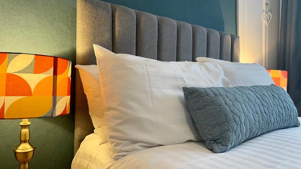 a bed with white pillows and a gray headboard at Lacet House in Ambleside