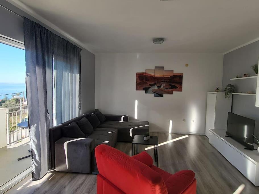 uma sala de estar com um sofá e uma grande janela em Apartman Valentina em Podstrana
