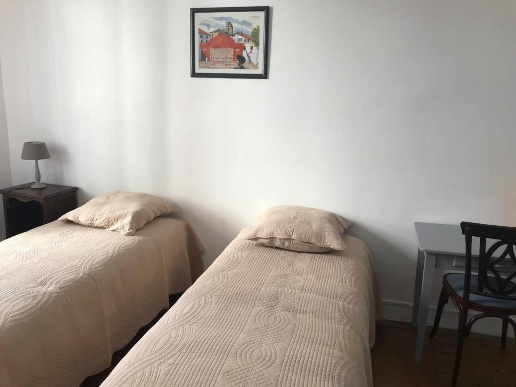 ein Schlafzimmer mit zwei Betten und einem Schreibtisch und einem Bild an der Wand in der Unterkunft Appartement confortable à Saint-Jean-de-Luz 45 m² avec cheminée in Saint-Jean-de-Luz