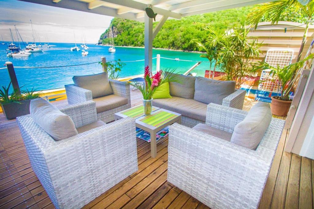 a patio with a couch and a table and the water at Appartement élégant à Deshaies avec terrasse privée, 80 m². in Deshaies