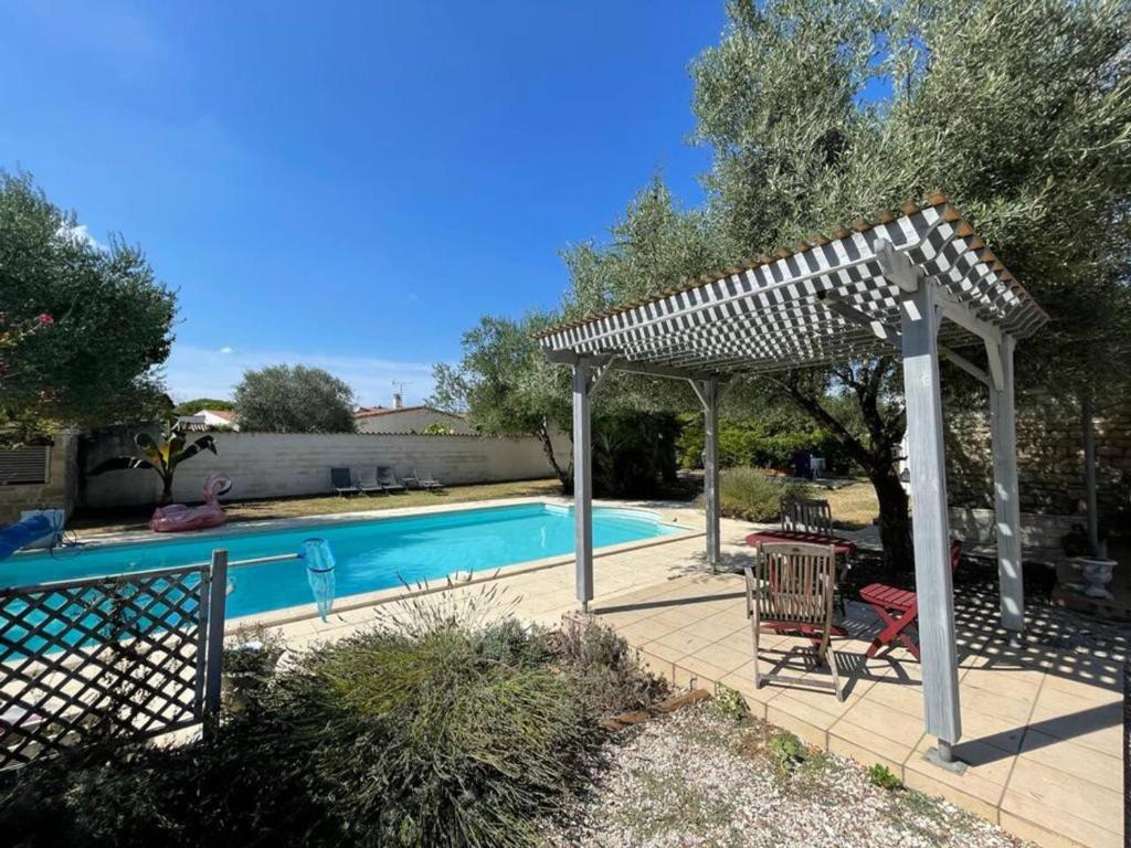 una pérgola junto a una piscina con mesa y sillas en Villa de 5 chambres avec piscine privee jardin clos et wifi a Saint Sulpice de Royan a 6 km de la plage, en Saint-Sulpice-de-Royan