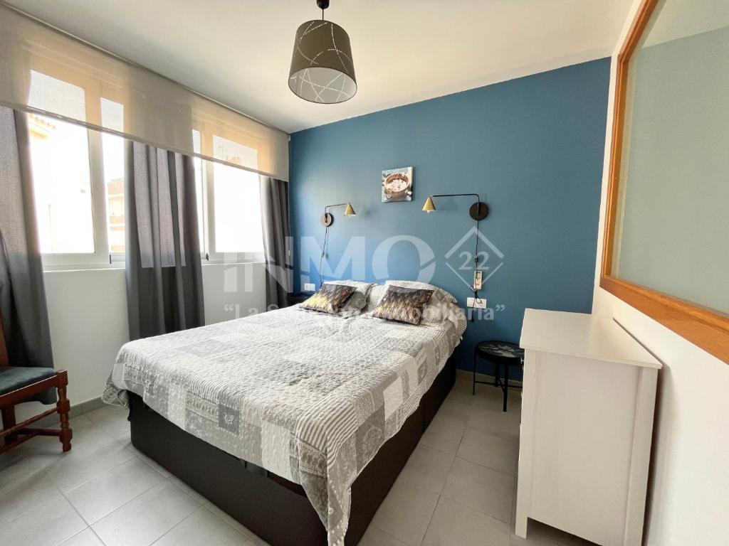 a bedroom with a bed and a blue wall at Bonito piso en pleno centro de Cambrils 101A - INMO22 in Cambrils