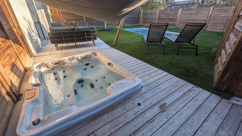 a hot tub on a deck with two chairs at Gîtes Domaine de la chapelle in Roquefort-les-Pins
