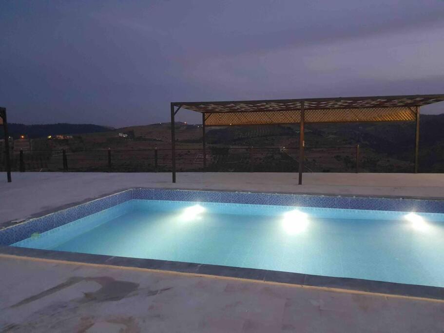 Breeze House في Kafr Khall: مسبح في الليل مع شرفة