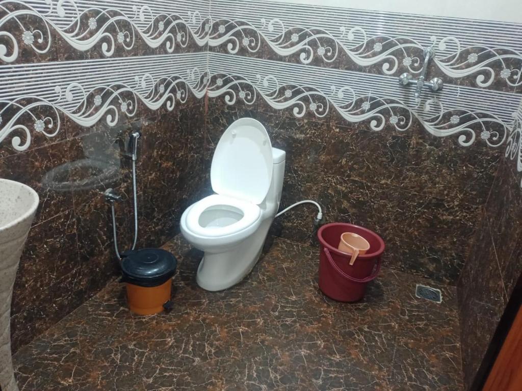a bathroom with a toilet and two buckets at TGI Guest Houses in Calangute