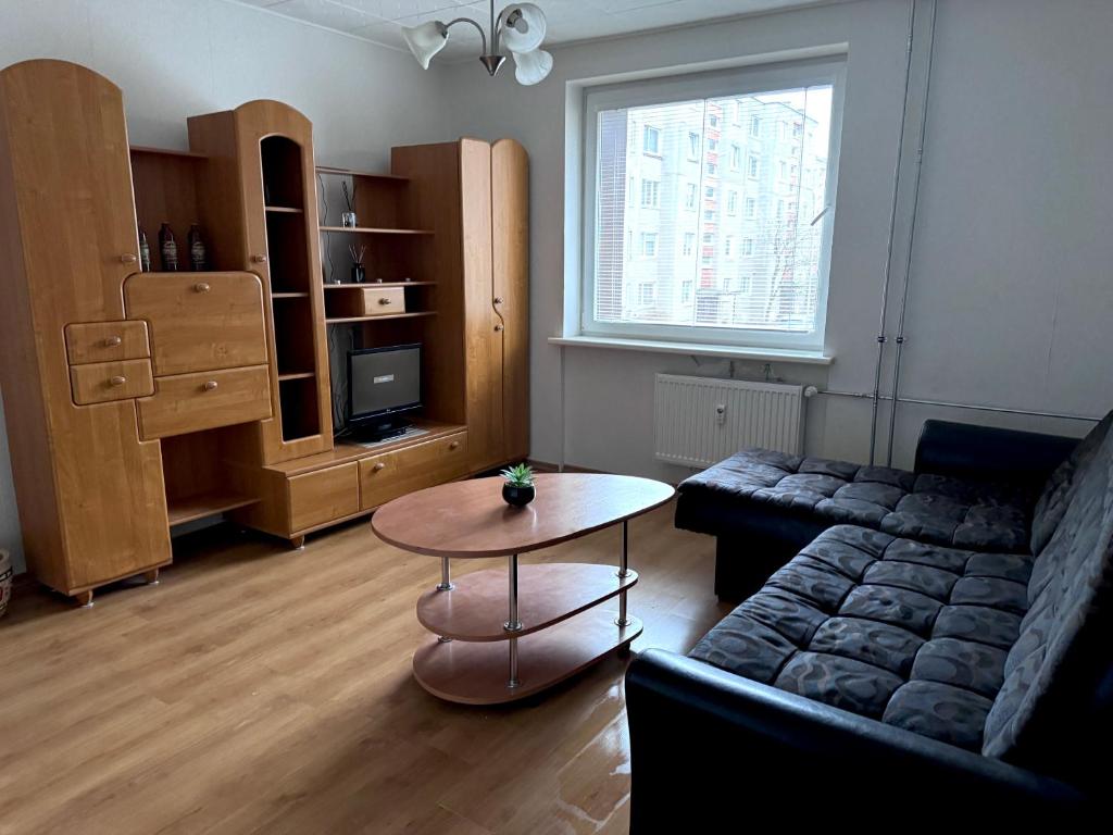 een woonkamer met een bank en een tafel bij Cozy Self Check-in CITY CENTRE apartment in Mažeikiai