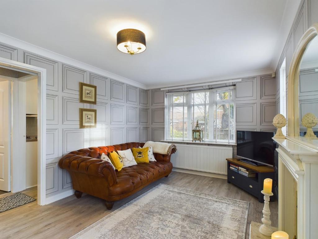 a living room with a brown couch and a television at Exquisite Bungalow in Hessle