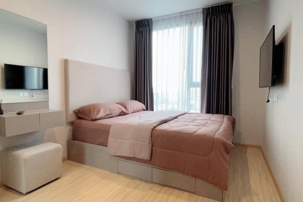 a bedroom with a bed with a television and a window at The Cozy, 3 min walk to MRT, 2 STN to Royal Palace in Bangkok Yai